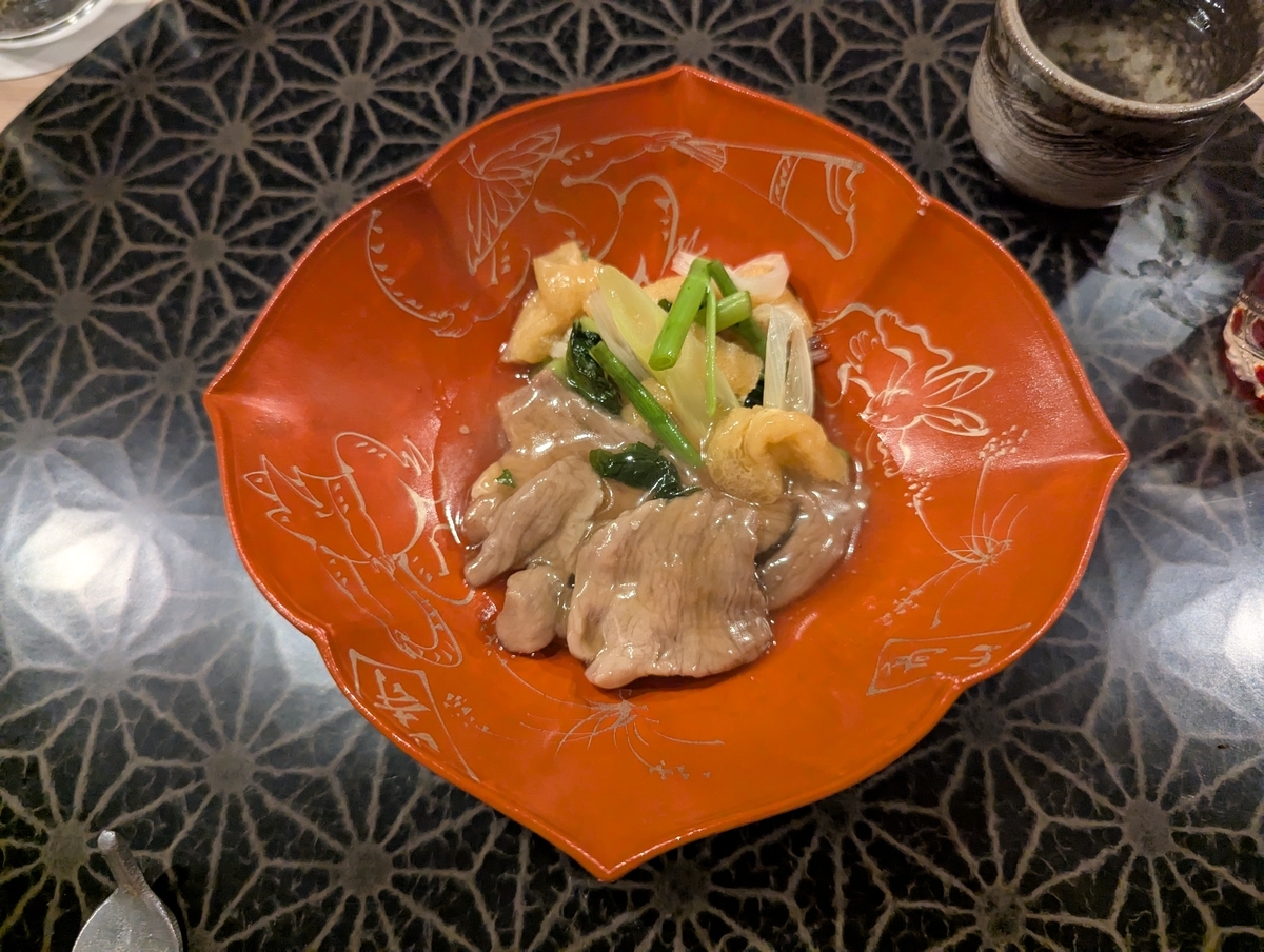 ほろりとやわらかな猪肉に、甘辛い出汁の旨みがじんわり広がる。器の赤が映える、滋味深い治部煮