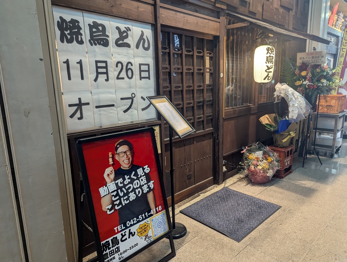 焼鳥どん豊田店の外観。2025年11月26日オープンの新店舗で、木格子のレトロな入口と「焼鳥どん」の提灯が目印。豊田駅徒歩1分の商店街にあり、動画で人気の日垣さんの看板も設置されている。