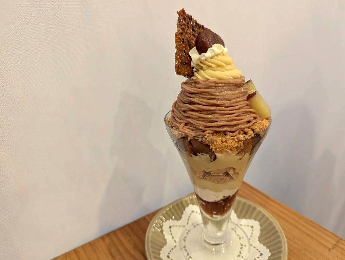 「栗とお芋のモンブランパフェ（税込1,400円）」のアップ写真。モンブランクリーム、栗、生クリーム、黒ごまチュイルが重なった多層パフェ。グラスに層がくっきり見え、濃厚でボリュームのある見た目。