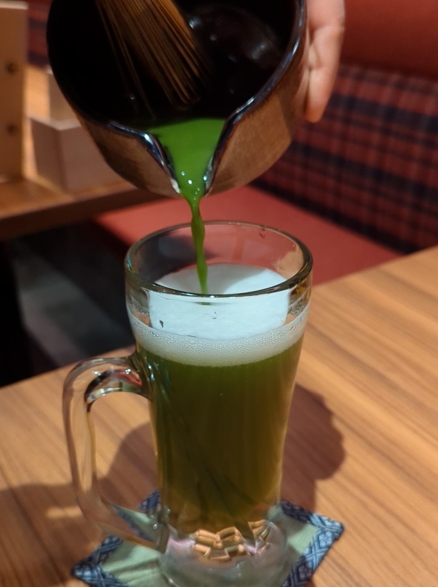 alt=大衆しゃぶしゃぶ勝治 上野御徒町店の抹茶生ビール。点てた抹茶を生ビールに注ぐ様子
