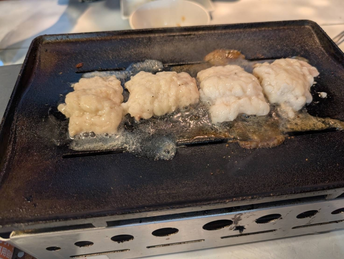牛シマチョーを鉄板で焼いている様子。白くぷっくりと膨らんだ状態で、脂がじわじわと溶け出している