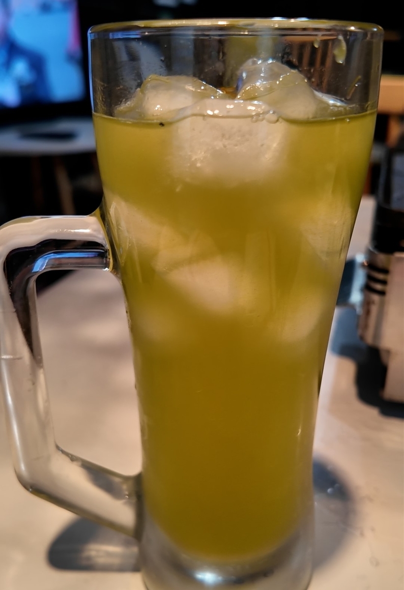 特製知覧緑茶割り。鮮やかな黄緑色の緑茶割りが氷入りのジョッキグラスに注がれている