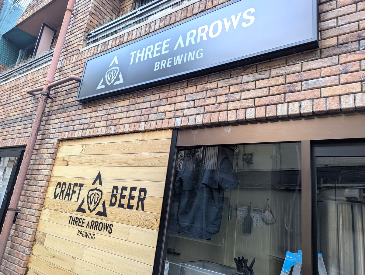 THREE ARROWS BREWINGのロゴサイン。矢印とシールドを組み合わせたブランドロゴとCRAFT BEERの文字が描かれている