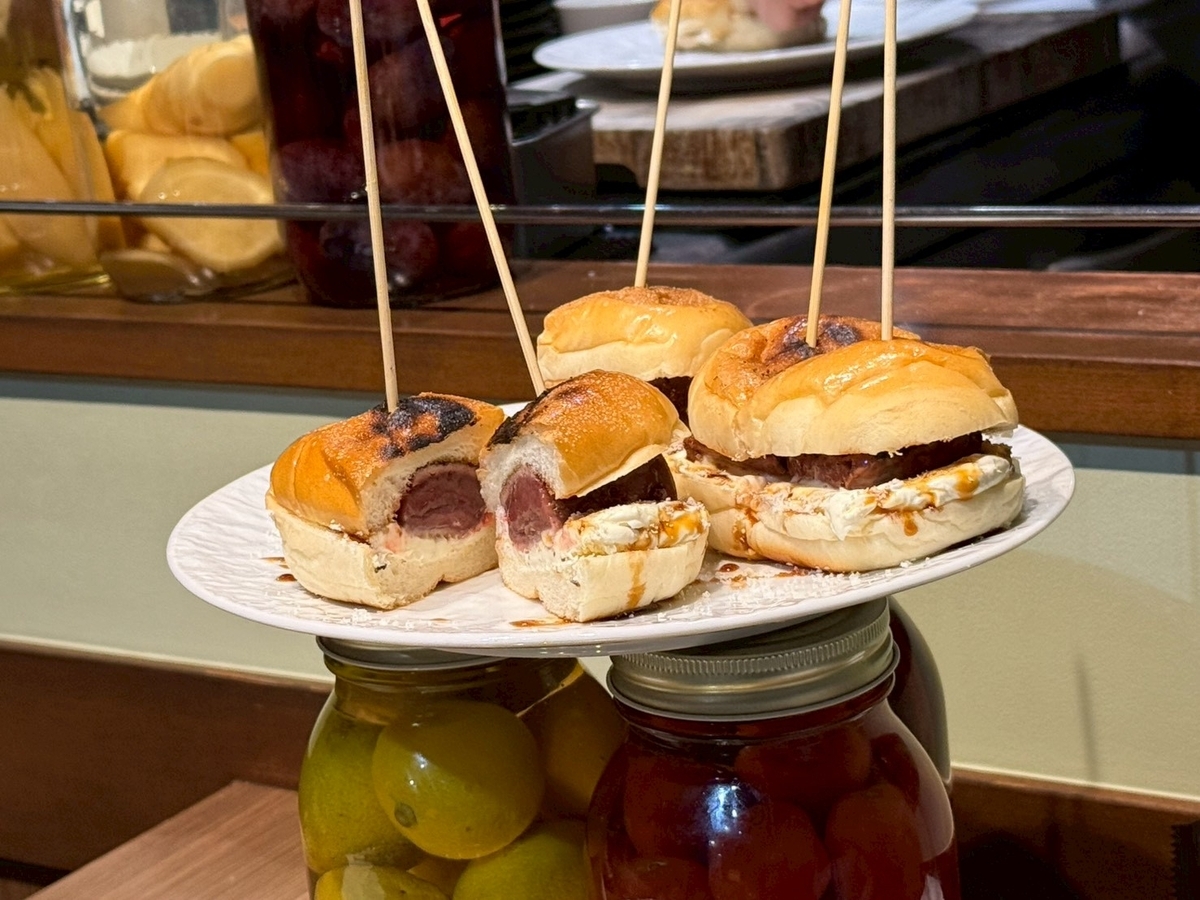 Beef Bossの名物レバーバーガー。炭火で焼き目をつけたバンズにレバーとチーズが挟まれ、断面からカシスソースが覗く。串が刺さった状態で5つ並ぶ