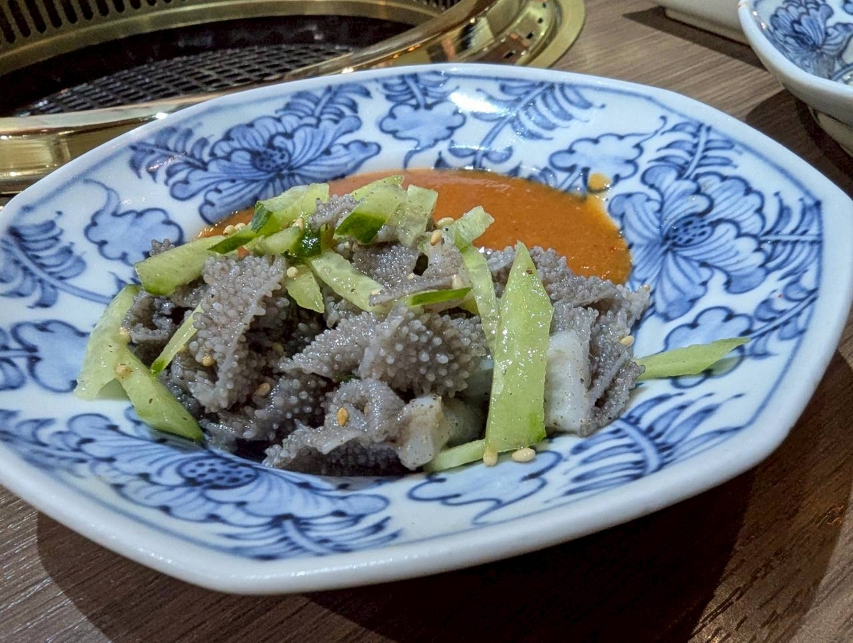 Beef Bossのセンマイ刺し。きゅうりと白胡麻を添え、藍色の染付皿に盛られている。酢味噌ダレが奥に見える
