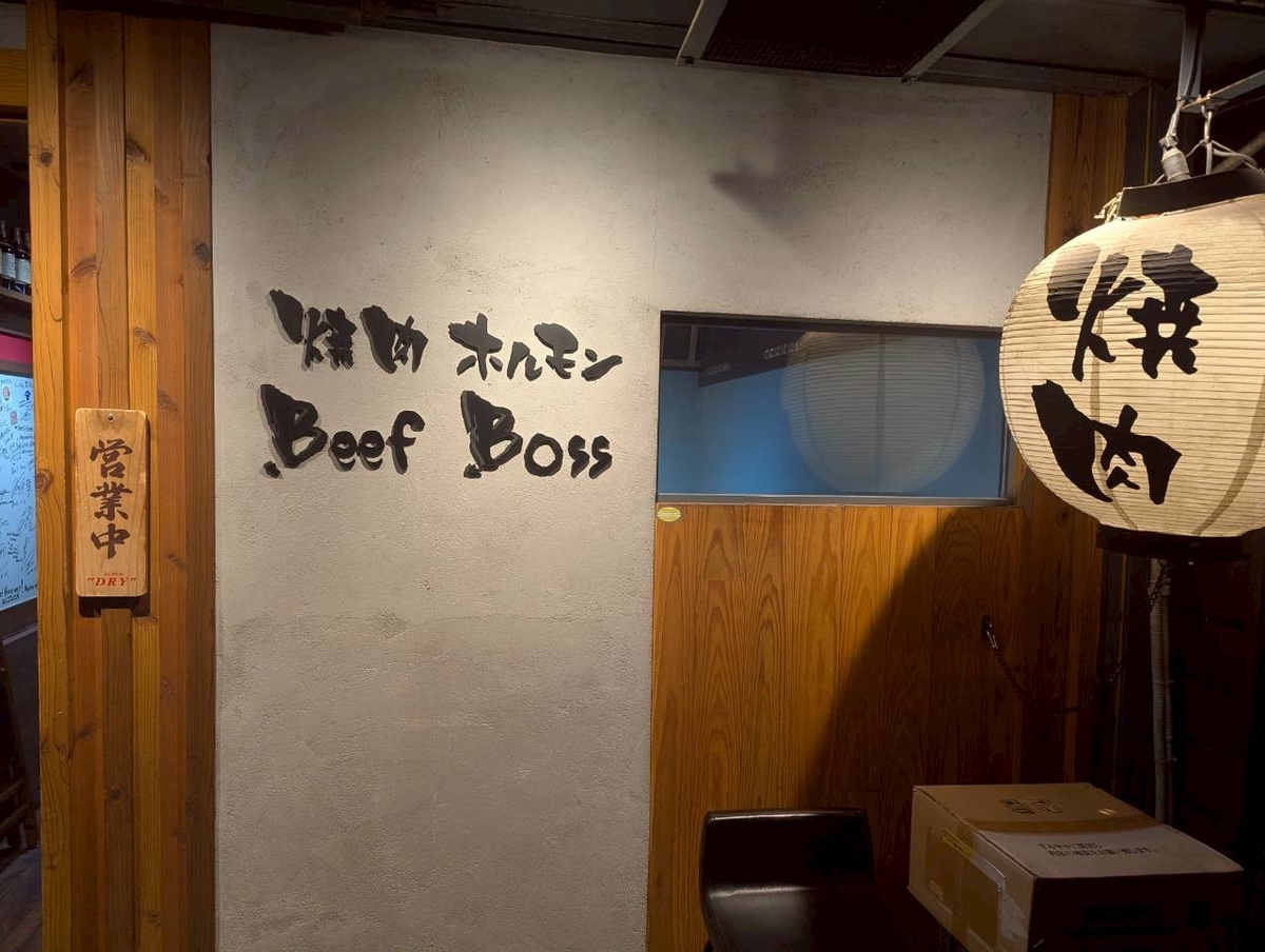 焼肉ホルモンBeef Bossの外観。コンクリート壁に筆文字の店名ロゴ、「営業中」の木札、「焼肉」と書かれた提灯が灯る