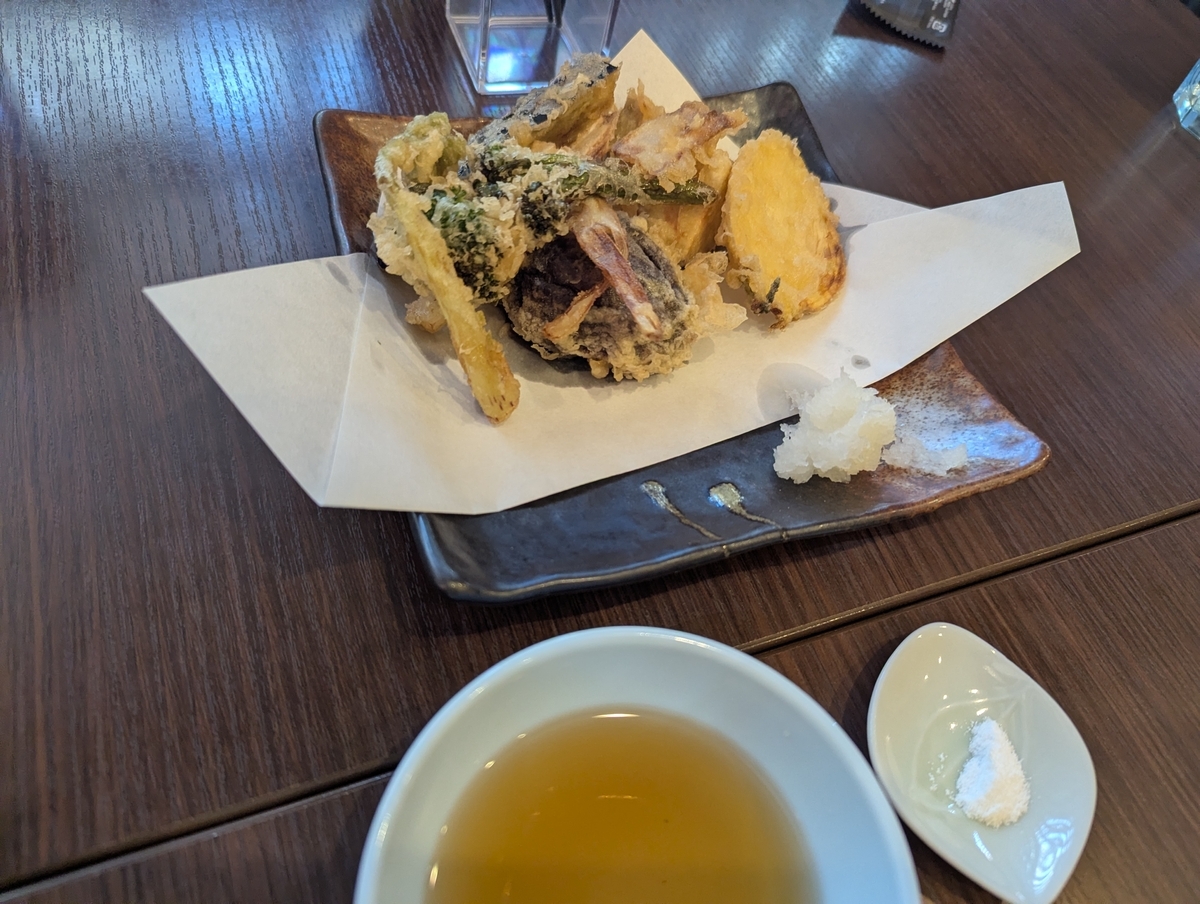 立川たかやの季節野菜天ぷら三種盛り。黒い角皿に紙を敷き、うど・人参・赤大根・しいたけなどの野菜天ぷらが盛られ、添えに大根おろしと天つゆ、塩が並ぶ