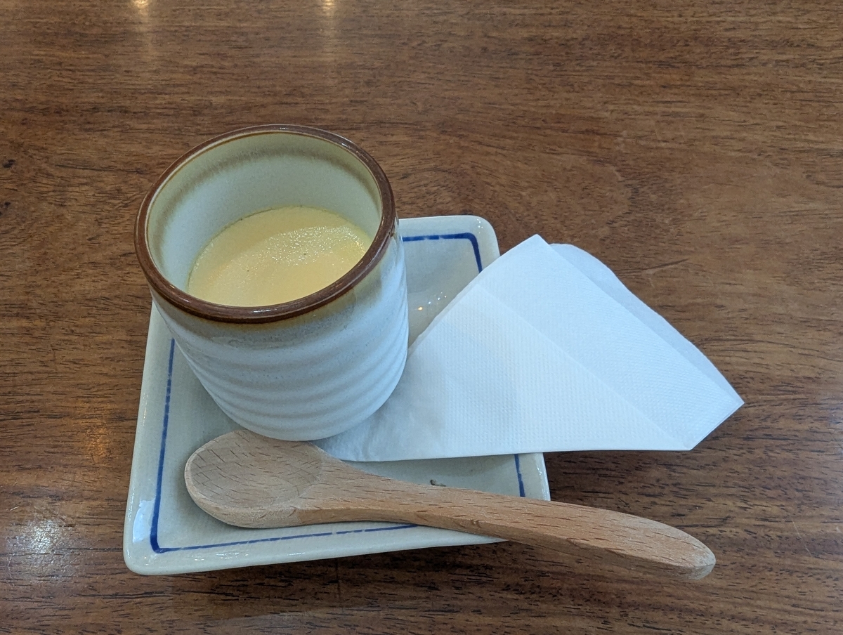 卵道（ランウェイ）の卵道プリン。陶器のカップに入った濃密な卵プリンに、木製スプーンが添えられた専門店ならではの一品