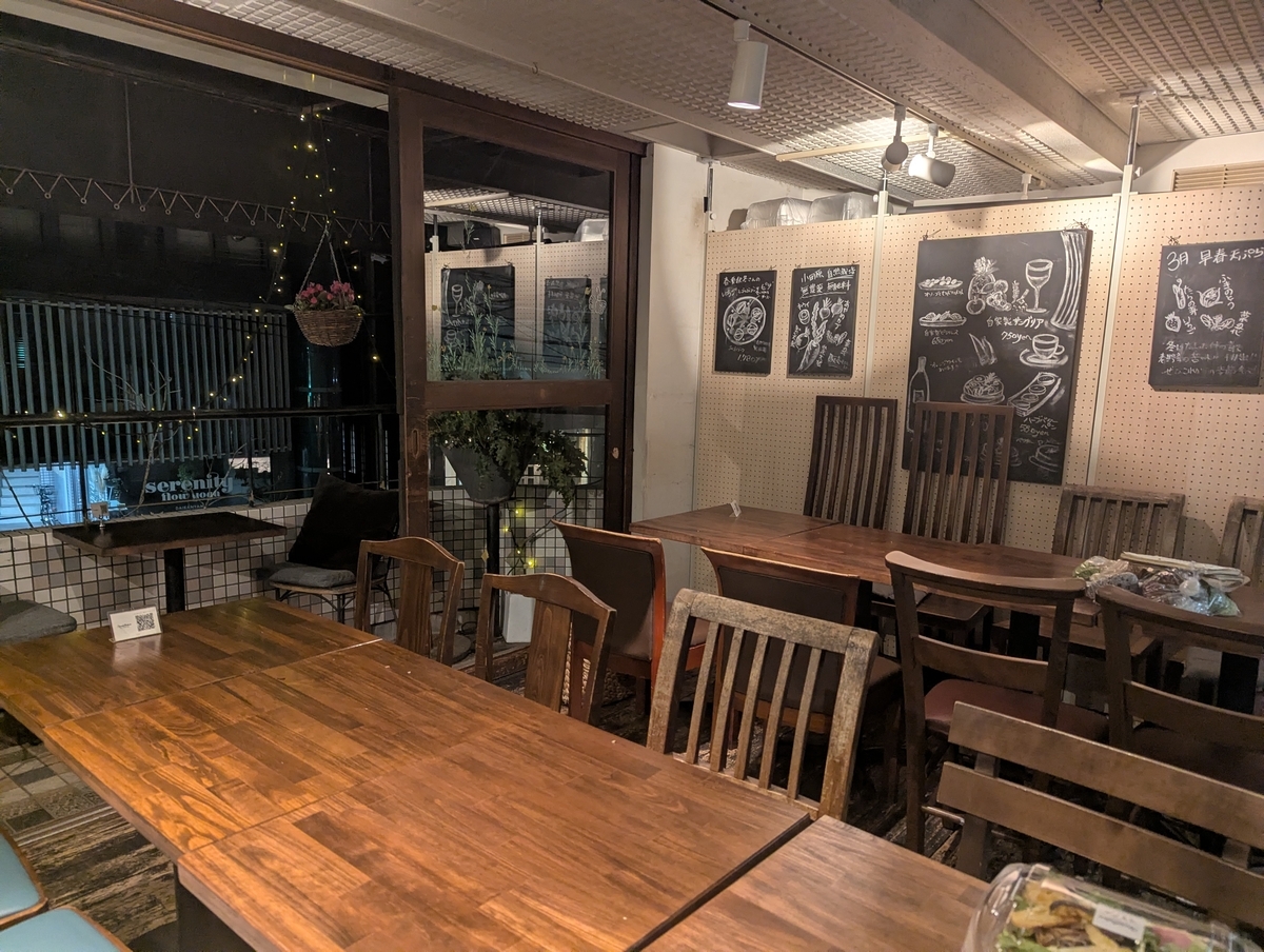 サンクスネイチャー恵比寿店の店内テーブル席、奥の壁には黒板アートで月替わりメニューが描かれる