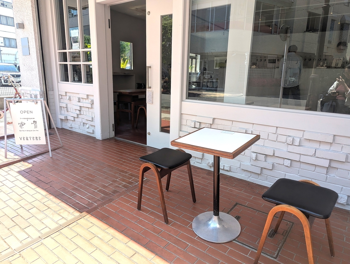 VERTERE Tachikawa Taproom（バテレ立川タップルーム）の外観。白壁とガラス張りの店先にテラス席と「フードのみ持ち込みOK」のOPEN看板が置かれている
