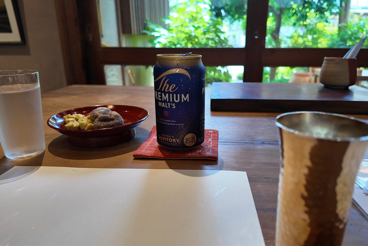 頑亭文庫のおまかせ缶ビール。この日はザ・プレミアム・モルツ。槌目のタンブラーと朱塗りの小皿のおつまみ