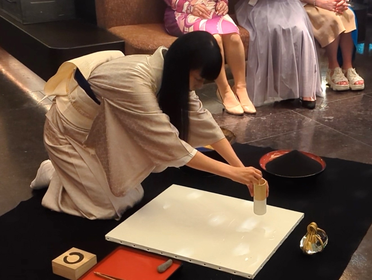 糊で書いた文字の上に金箔を散らす松井ユカ氏