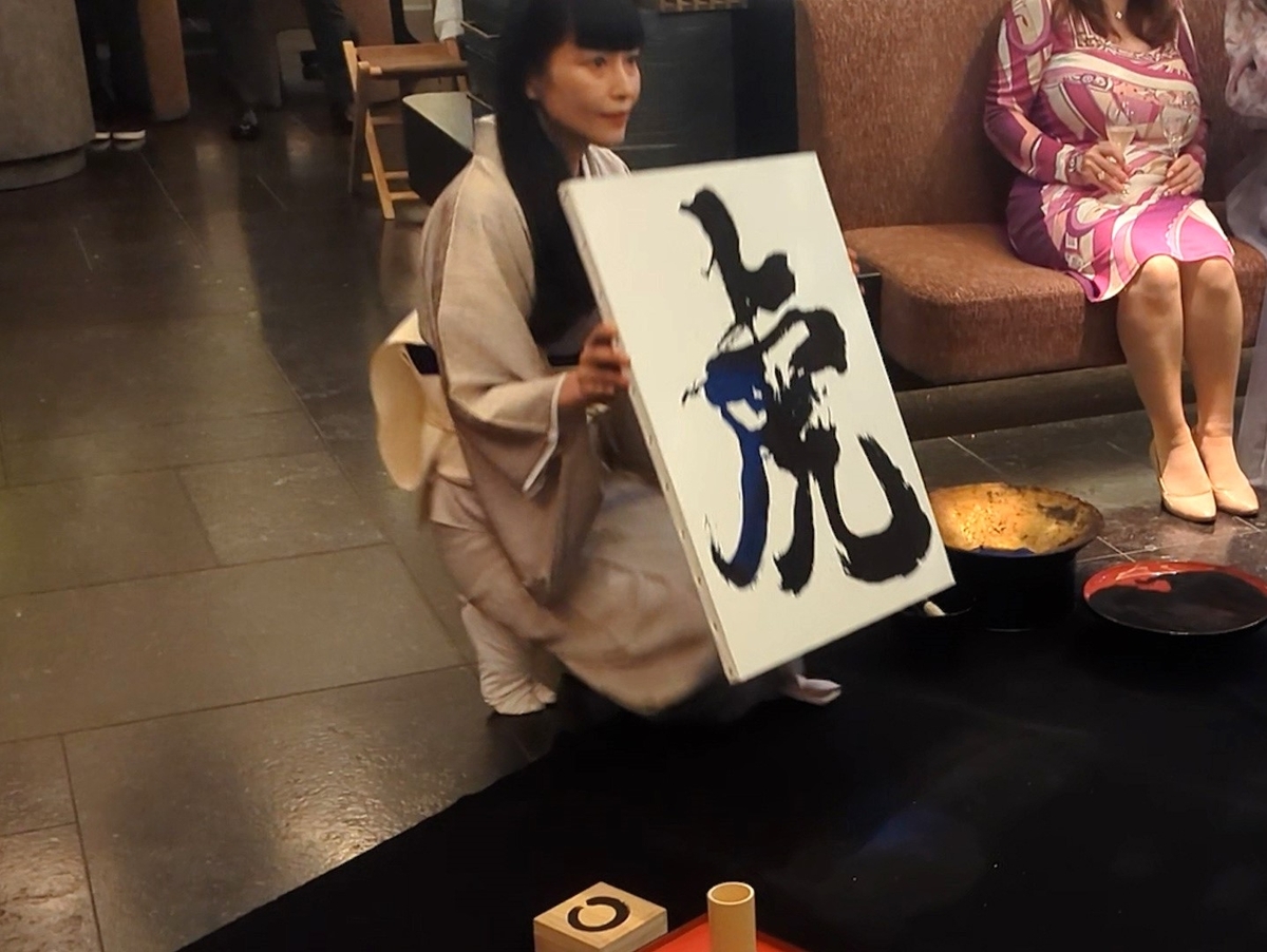 完成した砂のカリグラフィー作品「虎」を掲げる松井ユカ氏