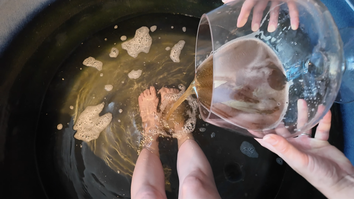 黒い陶器の水風呂にガラス容器からビールを注いでいるところ