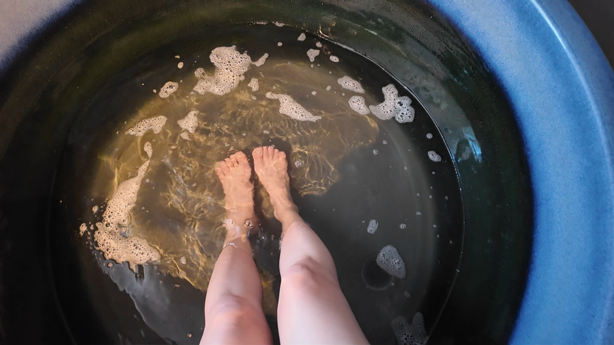 ビールを注いで泡が浮かぶ水風呂に足を入れているところ