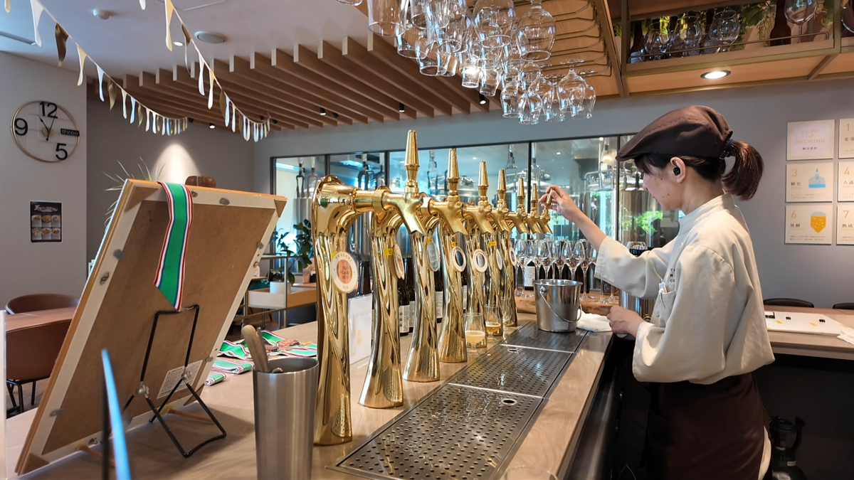 真鍮色のタップが並ぶカウンターで、スタッフがビールを注いでいる
