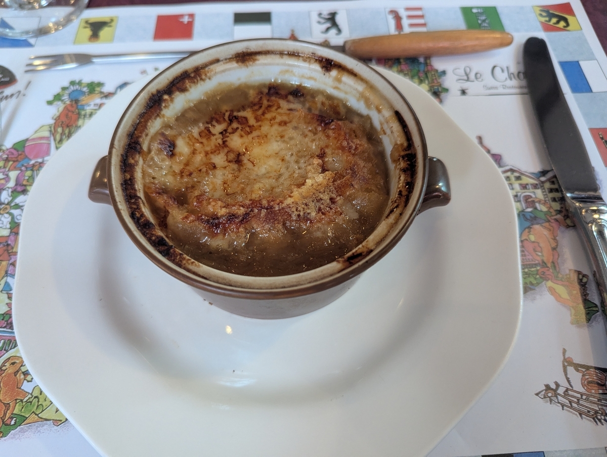 ル・シャレーの本日のスープ、オニオングラタンスープ。片手付きの耐熱ココットに、焼き目のついたチーズとパンが乗っている