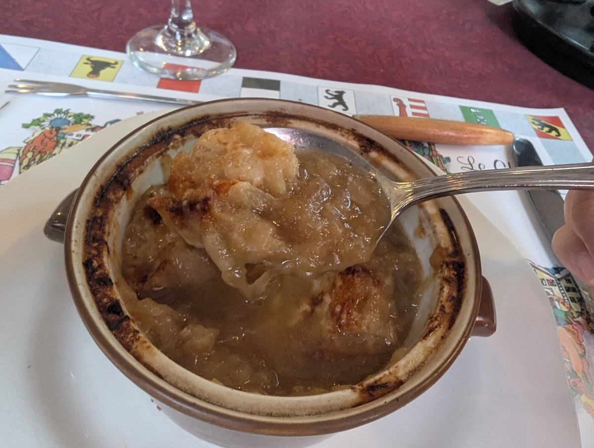 ル・シャレーのオニオングラタンスープをスプーンで掬ったところ。焼けたチーズの下から飴色に煮込まれた玉ねぎが現れている