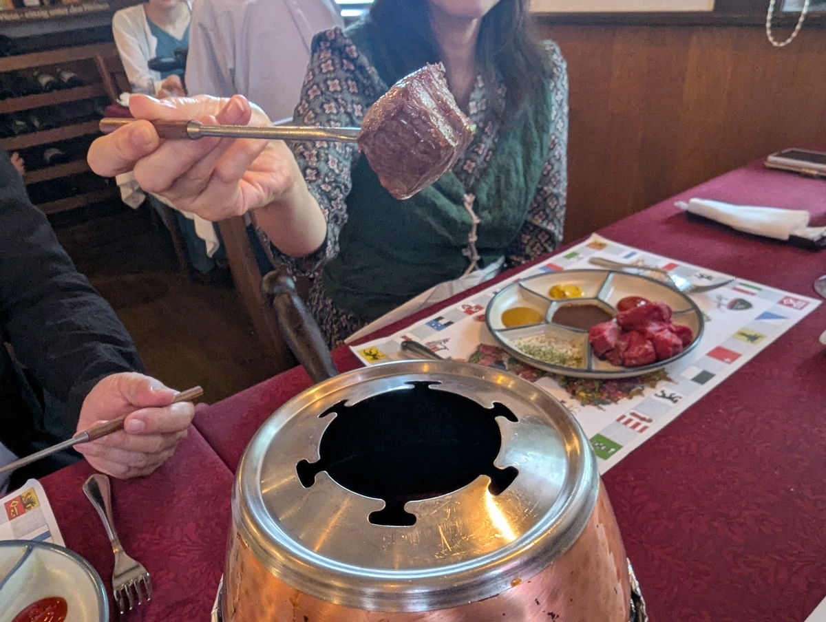 ル・シャレーのオイルフォンデュ。銅製の鍋から引き上げた、串に刺した牛ヒレ肉の一切れ