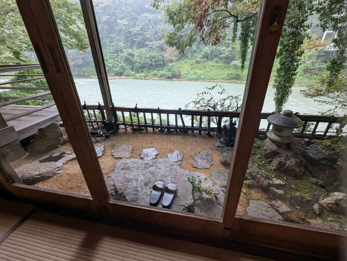 ままごと屋の個室の窓から見た庭。飛び石と灯籠、竹の柵の先に多摩川が流れる