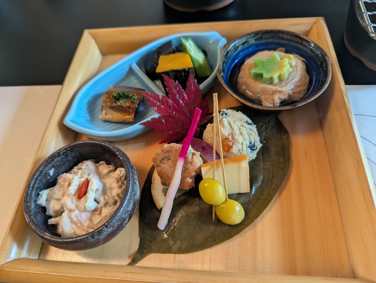 澤乃井ままごと屋の八寸盛り。木の折敷に白和え、うの花煎り、銀杏、紅葉の葉があしらわれている