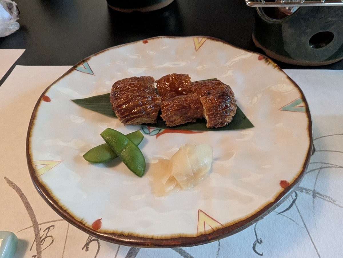 澤乃井ままごと屋の鰻もどき。笹の葉の上に蒲焼き風の豆腐料理、はじかみとえんどう豆が添えられている