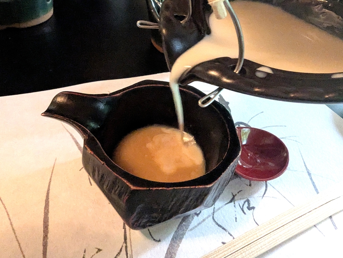 湯葉を食べ終えた後の豆汁を、いりこ酢の器に注いでスープにしているところ