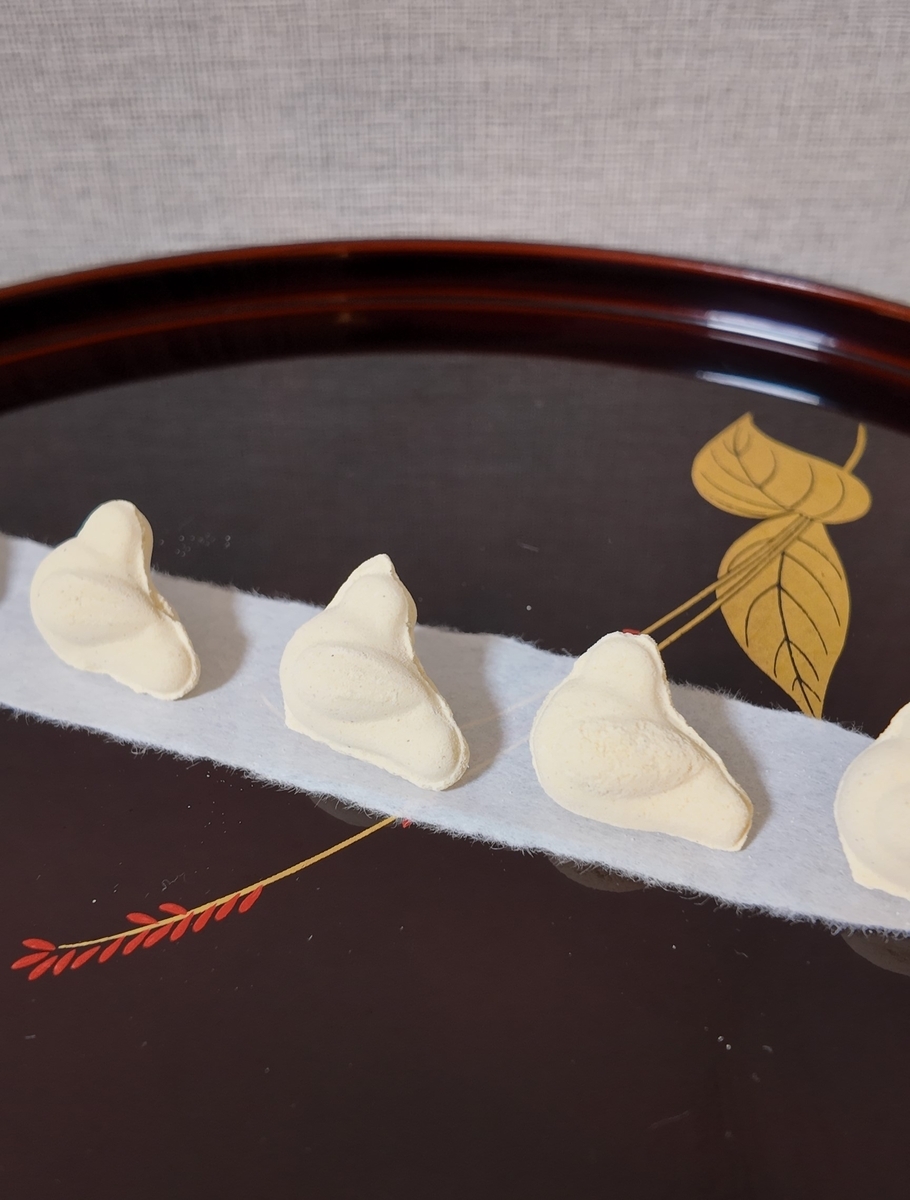 漆の盆に懐紙を敷いて並べた小鳩豆楽の干菓子