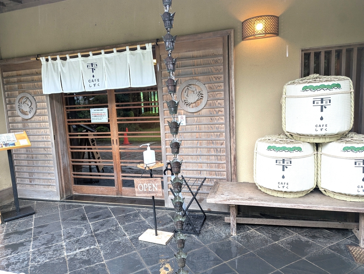 CAFE雫の入口に積まれた菰樽と白いのれん