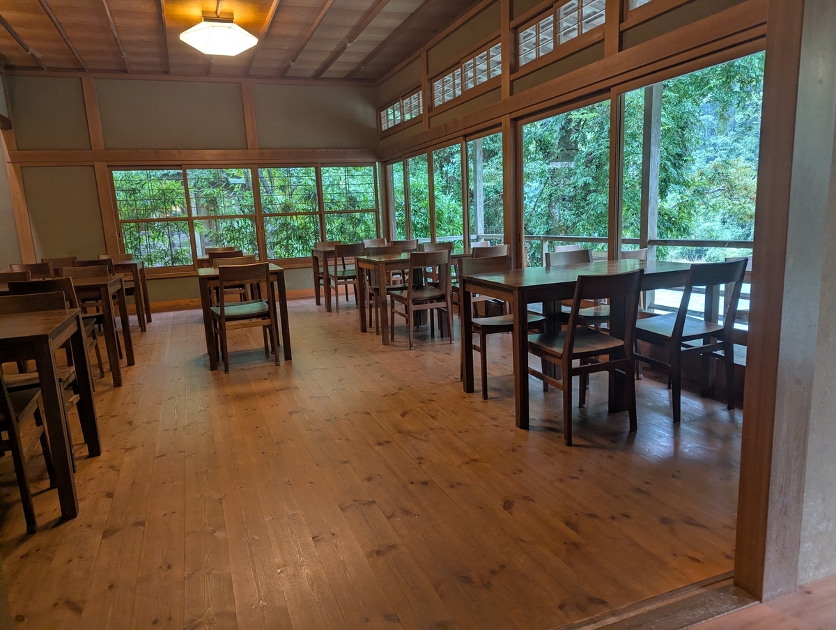 CAFE雫の店内。木のテーブルと格子窓、窓の外は御岳渓谷の緑