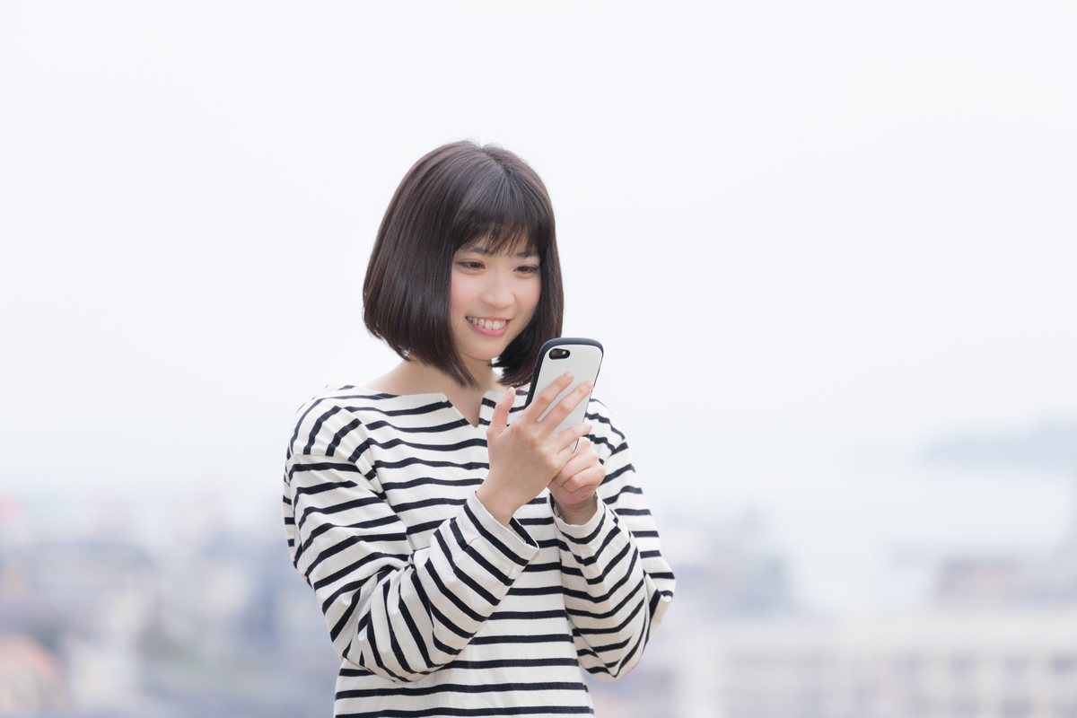 スマホを操作しながら微笑む女性