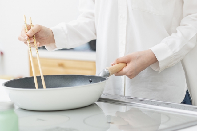 フライパンで料理をする女性の手