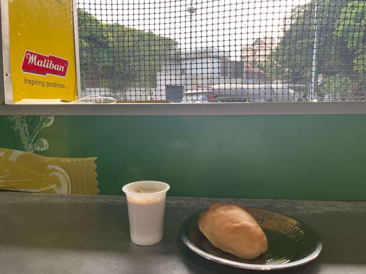 Palm Super Stallの店内で立ち飲みするキリテーとマールパン。窓越しに通りが見え、朝のローカルな雰囲気が伝わる。
