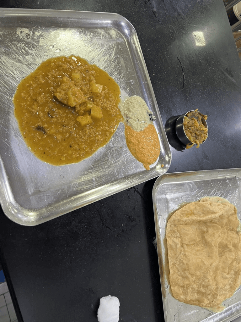 Ananda Bawanのプーリとサンバル。豆や野菜が煮込まれたカレーと、白いココナッツチャトニ、赤いチャトニが一緒に提供されている。