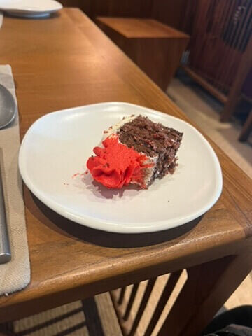 お客さんのお誕生日でいただいた、小皿にのったチョコレートケーキ一切れ。赤いクリームのデコレーション。