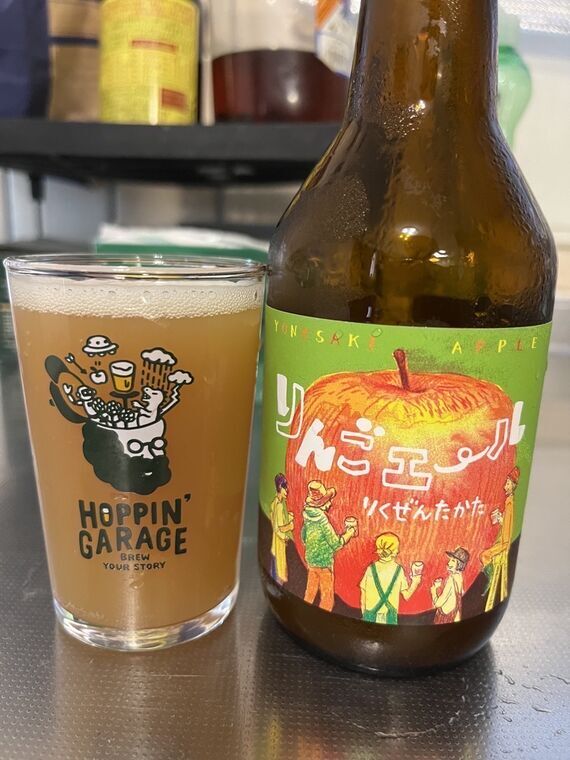 陸前高田マイクロブルワリーのりんごエール 瓶とHOPPIN GARAGEグラスに注いだ濁りのあるオレンジ色のビール