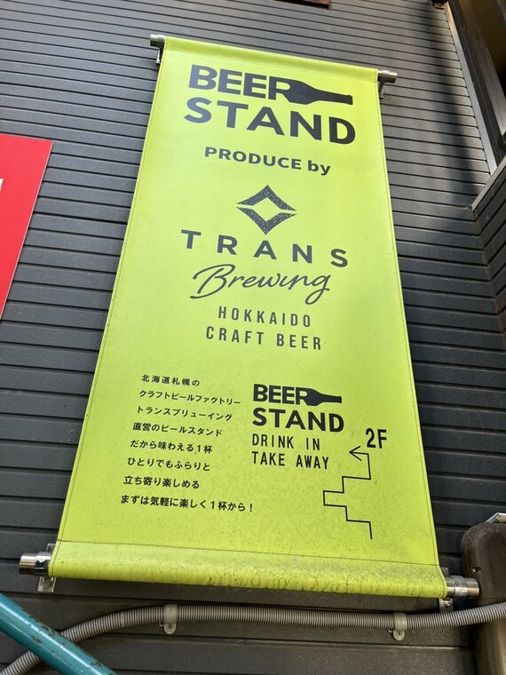 TRANS BREWING BEER STANDの黄色いタペストリー看板(PRODUCED BY TRANS Brewing HOKKAIDO CRAFT BEER 2F DRINK IN/TAKE AWAY)