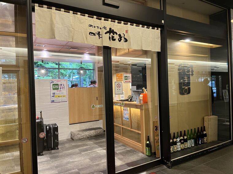町のすし家四季花まる時計台店の暖簾と受付と酒瓶の飾り