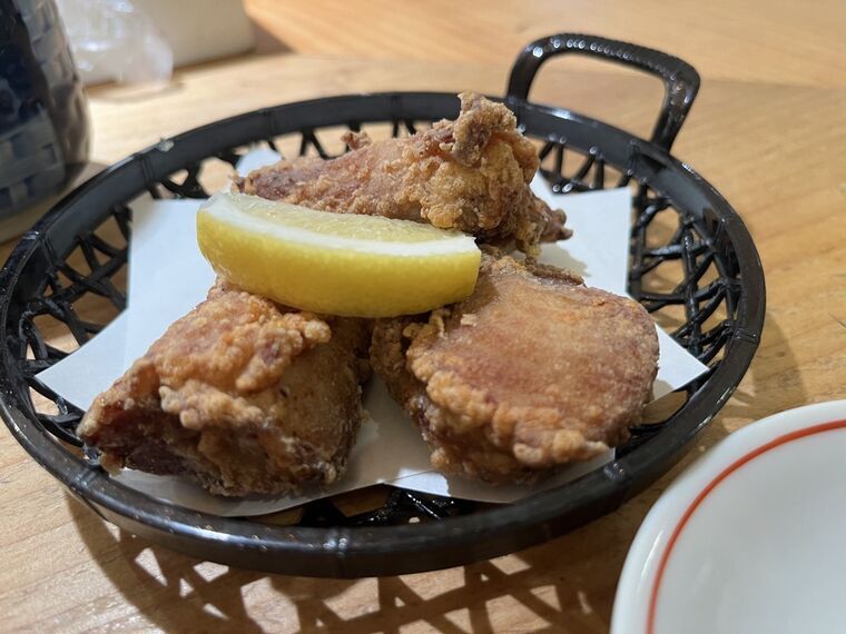 本鮪の尾の身竜田揚げ3個とレモンが盛られた黒いカゴ