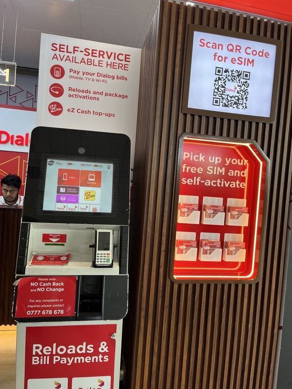 Dialogのセルフサービスコーナー。Pick up your free SIM and self-activateの棚とScan QR Code for eSIMの表示、Reloads and Bill Paymentsの端末