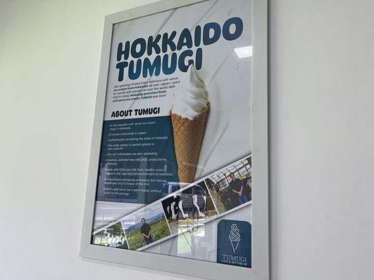 店内の額装ポスターHOKKAIDO TUMUGI。ABOUT TUMUGIとして北海道の人気店であることや生乳100%の説明が並ぶ
