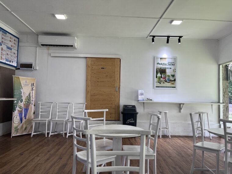 TUMUGIの店内席。白いテーブルと椅子、壁にJapanese Matcha Series NOW IN COLOMBOのポスター