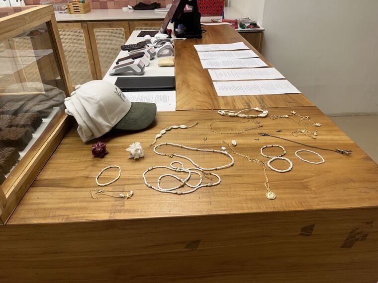 レジ横の木製カウンター。貝殻やパールのアクセサリー、キャップが並べられている