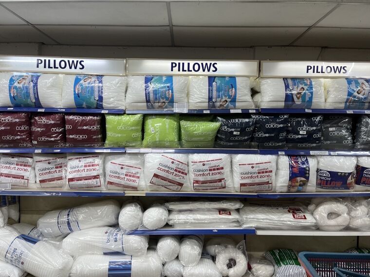Arpicoの枕・クッション売り場。PILLOWSの棚見出しの下に、袋入りの白い中身と色付きのクッションが並んでいる