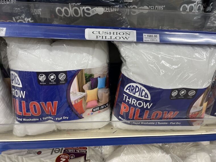 CUSHION PILLOWの棚札。Rs. 1565.00、THROW PILLOW 18X20 SUPERと書かれている