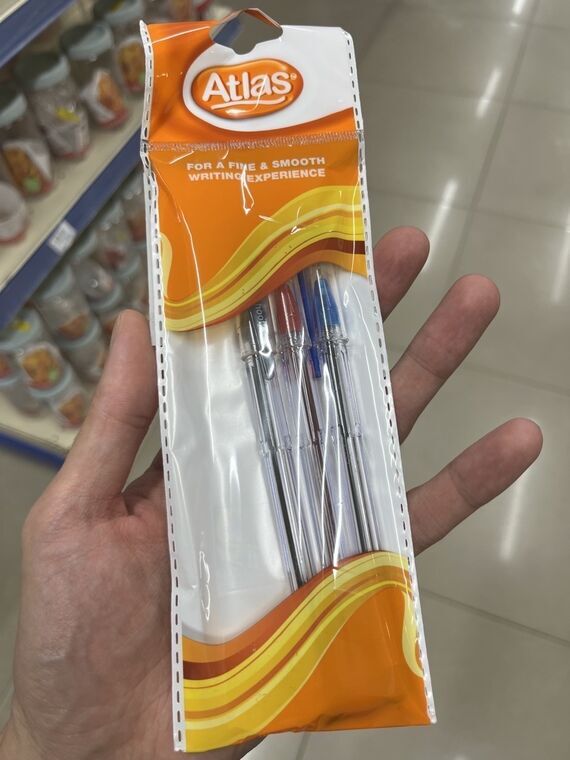 Atlasブランドの3色ボールペンのパッケージを手に持ったところ。FOR A FINE & SMOOTH WRITING EXPERIENCEと書かれている
