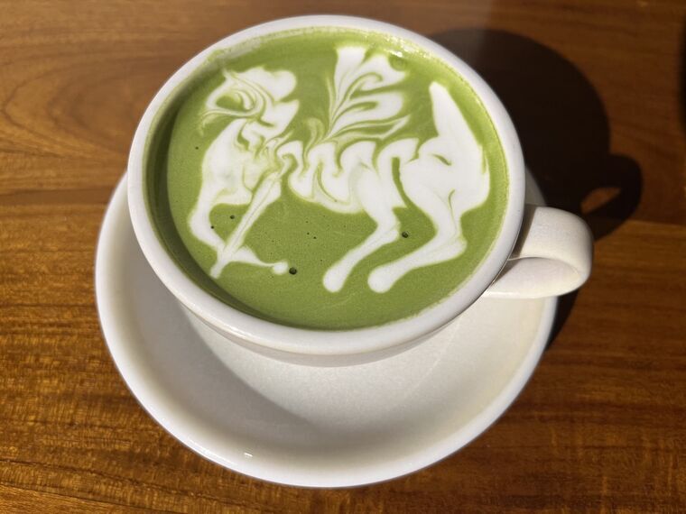 白いカップに入った抹茶ラテ。表面に馬のような動物を描いた精緻なラテアート