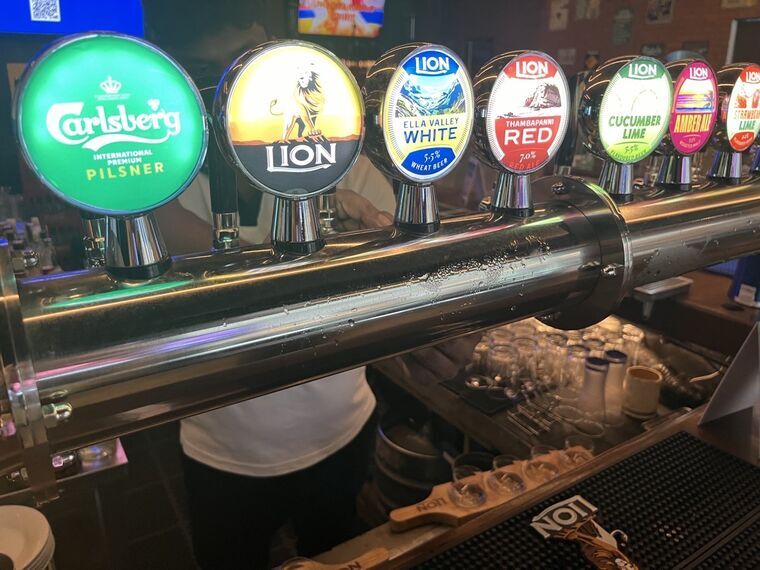 カウンターのタップバッジ。Carlsberg、Lion Ella Valley White 5.5% Wheat Beer、Lion Thambapanni Red 7.0% Red Aleなどのバッジが並ぶ