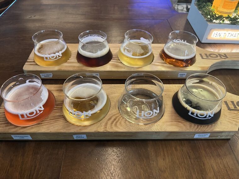 同じボードを斜め上から。各グラスの手前に白い札があり、ELLA VALLEY WHITE、AMBER ALE、STRAWBERRY LIMEなどの表記が読める