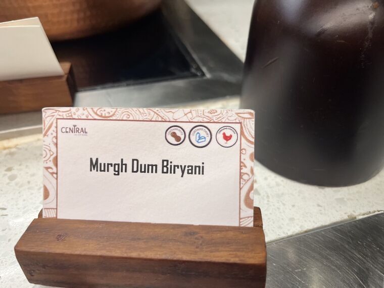 木製スタンドの名札にMurgh Dum Biryani。CENTRALのロゴとアレルゲンのアイコンが付いている